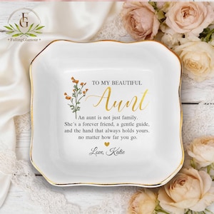 May include: A white ceramic trinket dish with a gold rim and floral accents. The dish has the text "TO MY BEAUTIFUL Aunt" and a loving message. The dish is a thoughtful gift for an aunt.