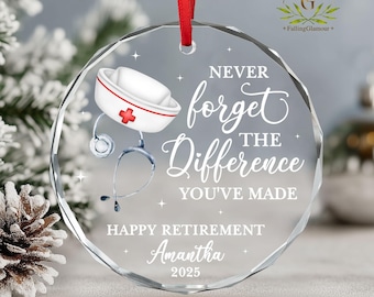 May include: A clear, circular glass ornament with a red hanging ribbon. The ornament displays a nurse's cap and stethoscope illustration, and the text "Never forget the Difference You've Made." It also includes "Happy Retirement" and a name and year.