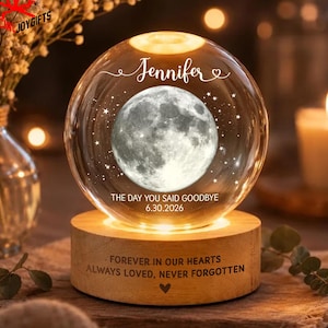 May include: A clear glass sphere night light featuring a detailed moon graphic, the name Jennifer, and the text THE DAY YOU SAID GOODBYE 6.30.2026. The sphere rests on a cylindrical wooden base engraved with FOREVER IN OUR HEARTS ALWAYS LOVED, NEVER FORGOTTEN.