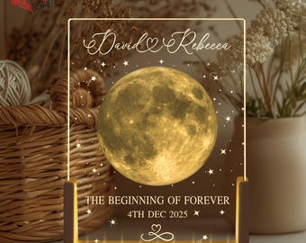 May include: A personalized LED night light with a full moon design. The names "David" and "Rebecca" are displayed above the moon, with the text "THE BEGINNING OF FOREVER" and the date "4TH DEC 2025" below. The light has a wooden base.