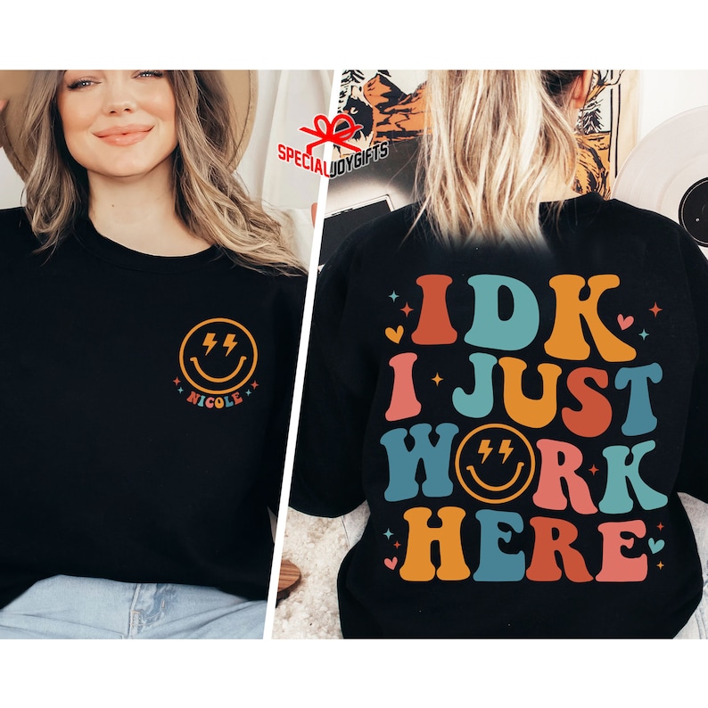 Pu&ograve; includere: Felpa nera con un design retr&ograve; colorato che dice "IDK I JUST WORK HERE" con una faccina sorridente nella parola "WORK". La parte anteriore della felpa ha una piccola faccina sorridente con fulmini e il nome "NICOLE" sotto.