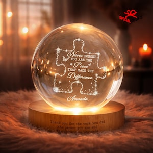 May include: A clear glass sphere lamp on a round wooden base. The sphere features an etched puzzle piece design with the text: Never forget you are the piece that made the difference, and the name Amanda. The base has engraved text.