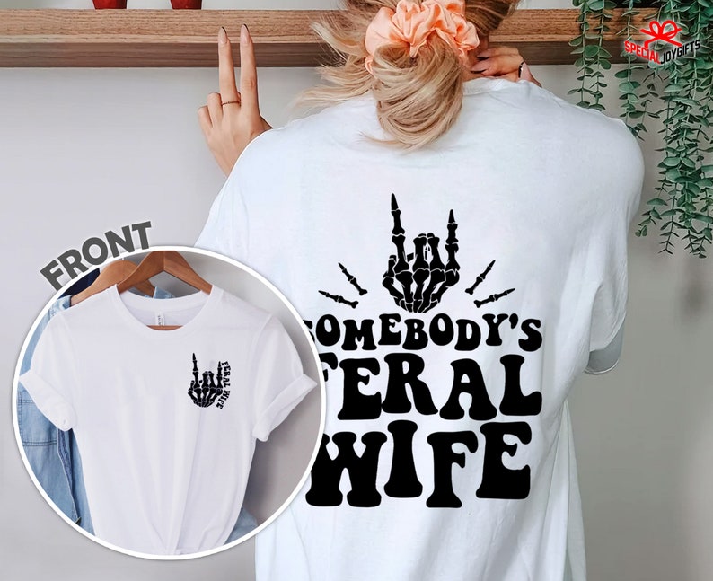 May include: White t-shirt with a black skeleton hand making a rock and roll sign and the text "Somebody's Feral Wife".