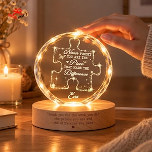 Peut inclure: Une plaque en cristal circulaire gravée d'une pièce de puzzle avec le texte, Never forget you are the piece that made the difference, et le prénom Eva. Elle repose sur un socle en bois gravé, Thank you for the work you did.