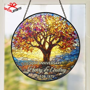 May include: A round stained glass window featuring a tree with colorful leaves in shades of red, orange, and yellow. The design includes the text "50th Anniversary," and the names "Henry & Audrey" with the date "07.28.1975."