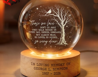 May include: A clear glass sphere lamp featuring an etched tree and bird design with the text: Those we love don't go away they walk beside us every day, unseen, unheard, but always near, so loved, so missed, so very dear. The wooden base reads: In loving memory of George L. Simpson 1937 - 2026.