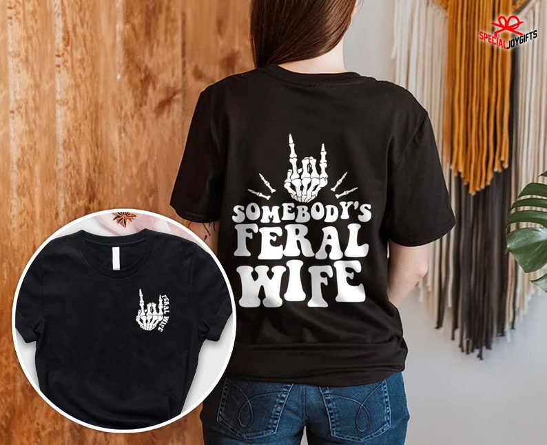 May include: Black t-shirt with a white graphic of a skeleton hand making a rock and roll sign with the text "Somebody's Feral Wife".