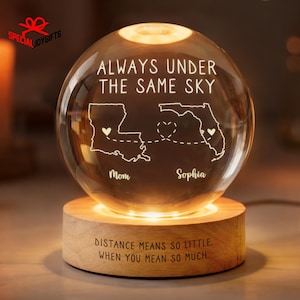 May include: A glowing glass globe with the text "ALWAYS UNDER THE SAME SKY" and state outlines of Louisiana and Florida. The globe sits on a wooden base with the text "DISTANCE MEANS SO LITTLE, WHEN YOU MEAN SO MUCH."