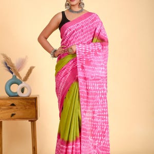 May include: A vibrant pink and green saree with a tie-dye pattern. The saree features a bold pink border and a contrasting green lower section. The pink section has a white tie-dye design. This traditional Indian garment is perfect for special occasions.