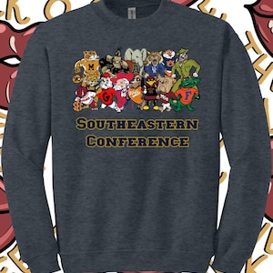 Peut inclure: Un sweat-shirt à manches longues gris chiné foncé avec une impression graphique représentant divers mascottes universitaires regroupées. Sous les mascottes, le texte SOUTHEASTERN CONFERENCE est imprimé en lettres capitales bleu foncé.