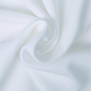 Puede incluir: Primer plano de tela blanca con un patr&oacute;n texturizado de puntos ligeramente en relieve. La tela est&aacute; drapeada en pliegues suaves, creando sombras y reflejos. El material parece ligero y transpirable, adecuado para ropa.