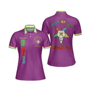 Puede incluir: Polo morado con las letras "OES" en verde, rojo y azul. La camisa presenta un cuello con rayas verdes, amarillas y azules, y la espalda muestra "ORDER OF THE EASTERN STAR" con un emblema de estrella. Las mangas tienen rayas a juego.