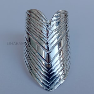 Pode incluir: Um anel de prata com um padrão de chevron. O anel é largo e tem uma ponta pontiaguda.