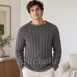 Peut inclure: Un pull à manches longues gris anthracite avec un motif en tricot côtelé vertical, une encolure ronde et des manches raglan. Le vêtement est porté sur un pantalon de couleur claire. Un filigrane avec le texte Stitchelle est visible.