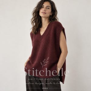 May include: A deep burgundy sleeveless knit sweater vest featuring a V-neckline and ribbed trim at the collar and armholes. The garment has a soft, fuzzy texture and is layered over dark trousers. A floral line art logo is visible on the front.