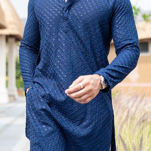 May include: A long-sleeved, dark blue, patterned shirt with a button-up collar. The shirt has a side slit and a textured fabric.