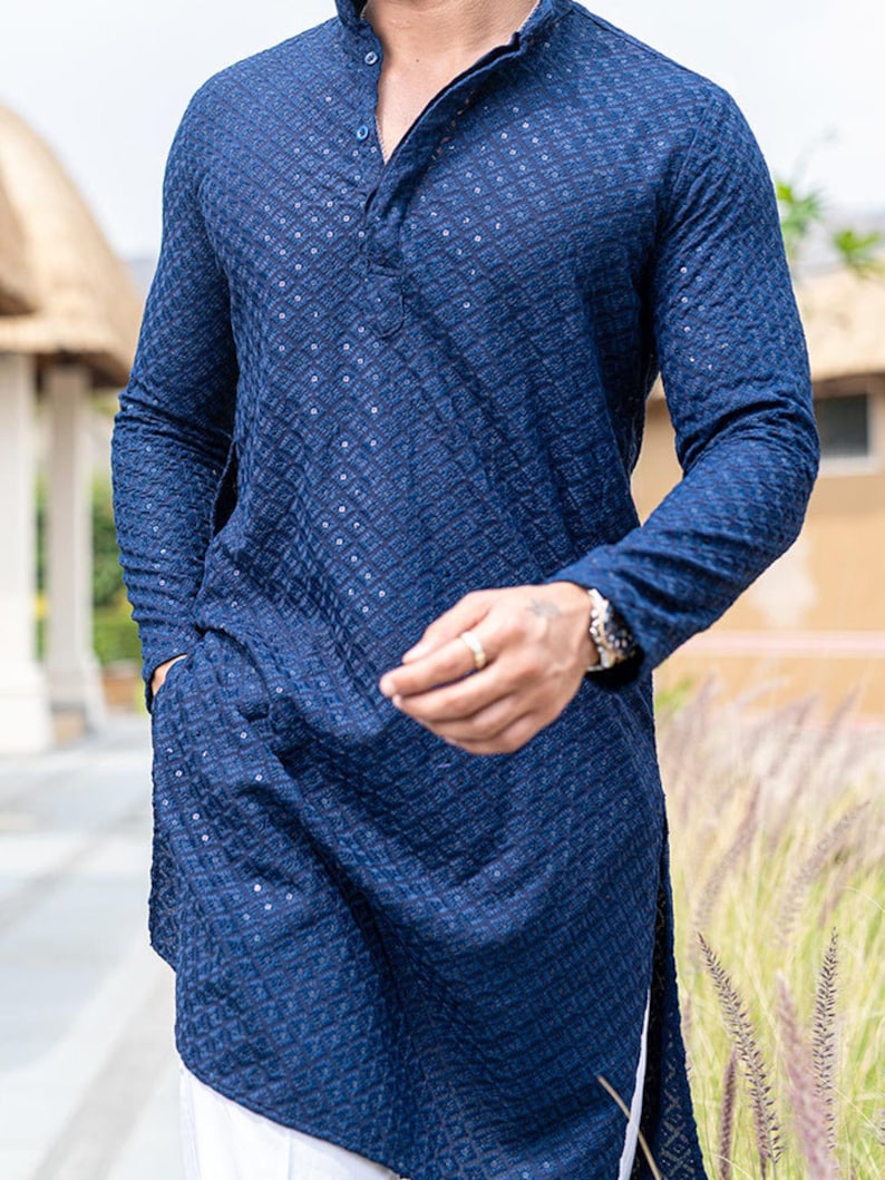 May include: A long-sleeved, dark blue, patterned shirt with a button-up collar. The shirt has a side slit and a textured fabric.