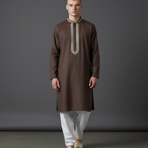 May include: A brown kurta with intricate embroidery around the collar and neckline, paired with white pants. The long-sleeved tunic features a mandarin collar and a straight hem. The image is labeled "WEDDING KURTA".