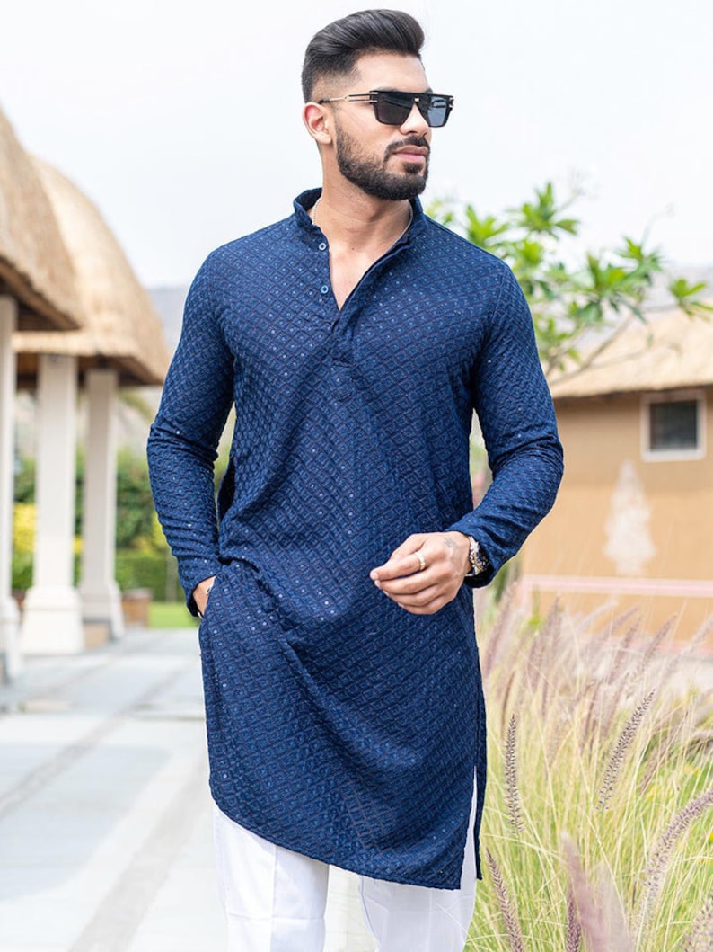 May include: A navy blue long-sleeved kurta with a geometric pattern. The kurta has a mandarin collar and a button closure. The model is wearing white pants.