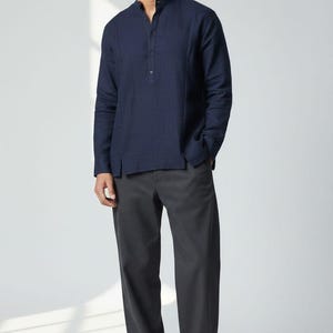 May include: A navy blue long-sleeve shirt with a mandarin collar and buttoned placket, paired with dark gray pants and white sneakers. The text "WEDDING KURTA" is visible at the bottom left.