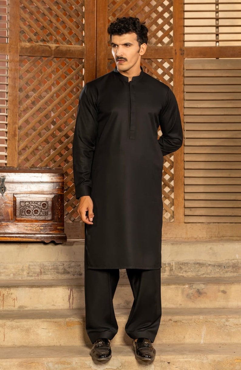 May include: A black long-sleeved shirt with a mandarin collar and a button closure. The shirt is paired with black pants and black shoes.