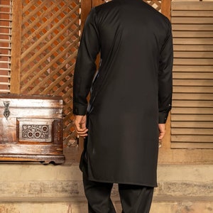 May include: A black long-sleeved shirt with a high collar and a matching pair of black pants. The person is standing on a set of stairs.