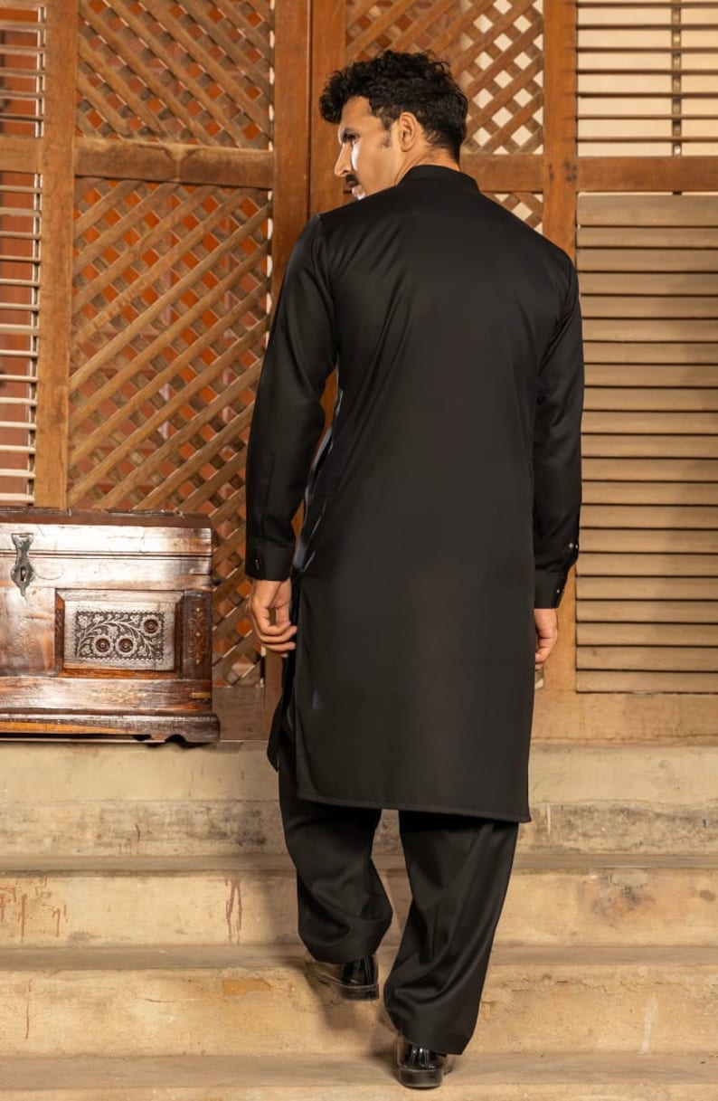 May include: A black long-sleeved shirt with a high collar and a matching pair of black pants. The person is standing on a set of stairs.