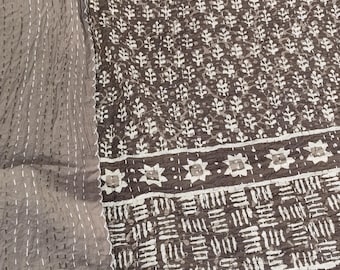 Puede incluir: Un edredón con estampado marrón oscuro y blanco con un diseño floral. El edredón tiene un borde con un patrón geométrico y costuras blancas. Una tela gris sólida con costuras blancas está en el lado izquierdo.