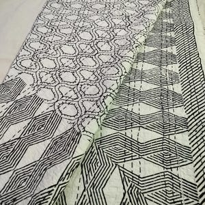 May include: White and black patterned quilt with geometric and organic designs. The quilt features a variety of patterns, including interlocking circles, zigzags, and diamond shapes. The stitching is visible, adding texture and detail to the overall design.