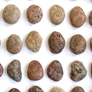 May include: A collection of 40 smooth, round, multi-coloured stones with a speckled pattern. The stones are arranged in rows on a white background.