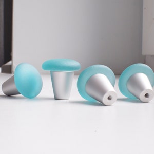 May include: Four frosted glass cabinet knobs with a light blue finish and a silver base.