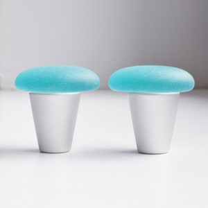May include: Two light blue glass mushroom-shaped knobs with silver bases.