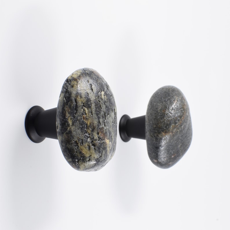 Coastal pebble knobs mounted on a rustic nightstand, emphasizing smooth surfaces and one-of-a-kind natural shapes. Perfect for drawers, bedside tables, or chests, these handmade beach stone handles add tactile charm and understated elegance, enhancing modern farmhouse, Scandinavian, or bohemian interiors with organic, handcrafted accents.