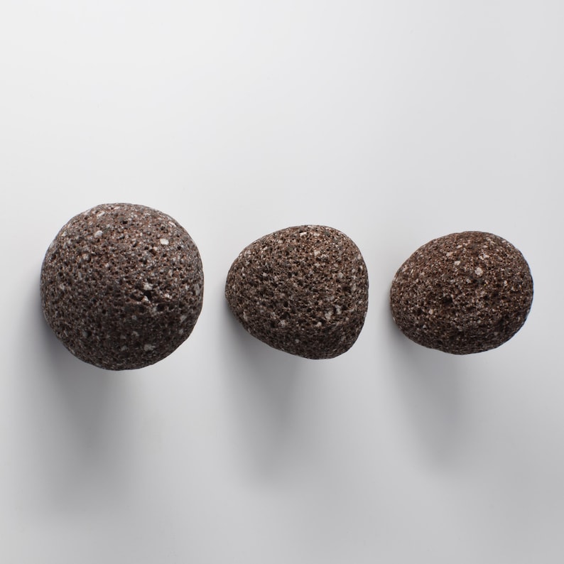 White stone round hook with brass fitting installed on a bathroom wall. The elegant simplicity of the stone contrasts beautifully with the sturdy brass screw, providing a functional and aesthetically pleasing addition to any modern or rustic bathroom. Ideal for hanging towels, robes, or other small accessories with ease