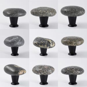 Polished natural stone knobs installed on a wooden dresser, emphasizing subtle coastal textures and unique pebble shapes. These handmade beach stone pulls are perfect for drawers, sideboards, or cabinets, adding an organic, tactile accent to furniture while enhancing Scandinavian, modern rustic, or bohemian interior designs with understated elegance.