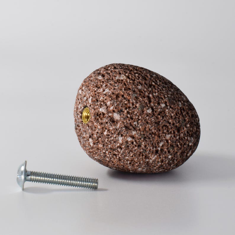 Close-up view of a grey stone round hook mounted on a bathroom wall. The deep drill and secure brass fitting ensure that the hook is both sturdy and easy to install. This versatile hook is perfect for hanging towels, robes, or even jewelry, combining functionality and style for a modern, nature-inspired aesthetic