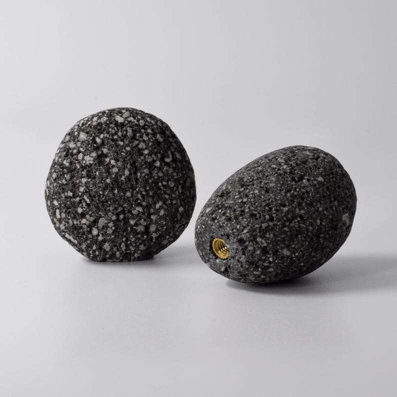 A variety of natural stone hooks in brown, grey, and white colors laid out on a wooden surface, showcasing their smooth round shape and brass fittings. Each hook is designed for easy mounting on walls, cabinets, or doors, adding a natural, earthy touch to your living space while providing durable and practical functionality