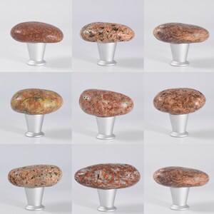 Natural rock cabinet knobs for kitchen, storage units, and furniture – Featuring real sea stones attached to a black metal base, these unique drawer pulls enhance a variety of furniture pieces, including kitchen cabinets, wooden chests, bedside tables, and media consoles. Their smooth, rounded shape ensures a comfortable grip, while their earthy aesthetic makes them ideal for coastal, industrial, and rustic decor. Each stone varies in shape, making every handle one of a kind.