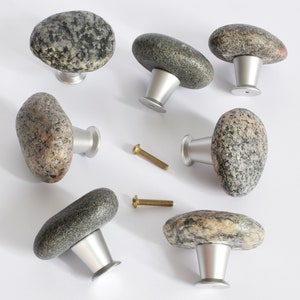 May include: Seven natural stone cabinet knobs with silver metal bases. The knobs are various shades of grey and brown with a speckled pattern.