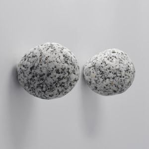 May include: Two round, smooth, gray and white speckled stone knobs.