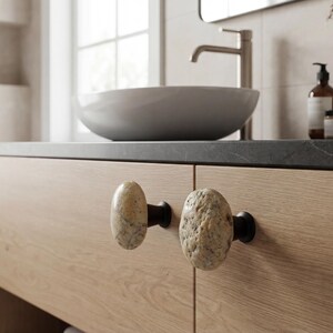 Artisan-crafted rock knobs on a sideboard, emphasizing irregular shapes and smooth, polished finishes. These handmade beach stone drawer pulls are ideal for cabinets, storage units, or nightstands, adding tactile and visual appeal while enhancing interior design with coastal elegance, rustic charm, and natural, one-of-a-kind beauty.