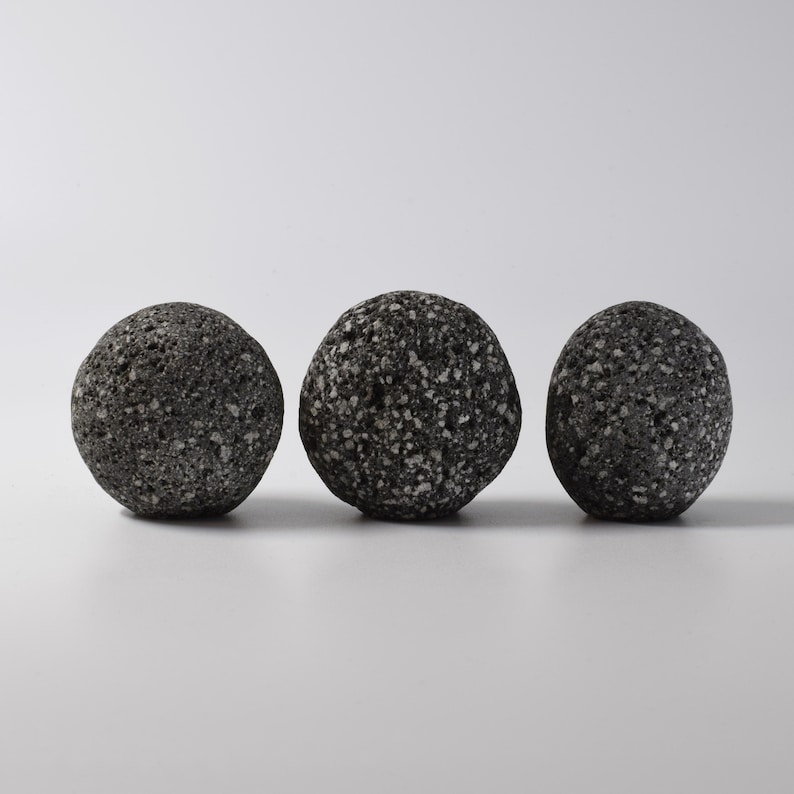 Close-up of a grey stone knob being installed into a wooden cabinet door with a brass threaded fitting. The deep drilled stone and precision threading ensure a secure, tight fit, making it easy to add a touch of nature to your home decor. This simple yet stylish stone knob is perfect for use as a hook or drawer pull