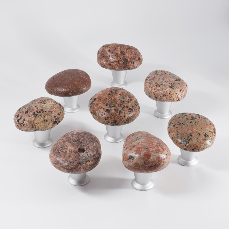 Unique beach stone knobs on a wooden chest of drawers, highlighting smooth, organic pebble forms. These handmade drawer pulls provide functional hardware while adding tactile and visual interest, enhancing coastal, Scandinavian, or farmhouse interiors, and giving furniture a one-of-a-kind handcrafted accent that complements natural and modern home decor.