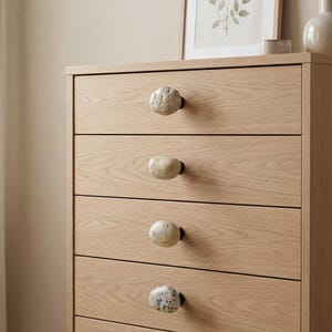 pebble drawer pulls on a modern kitchen cabinet, highlighting the irregular shapes and earthy tones. These beach stone handles bring a natural, tactile touch to drawers, sideboards, and cupboards, perfect for Scandinavian, farmhouse, or bohemian interiors seeking subtle coastal charm and durable, handcrafted furniture hardware.