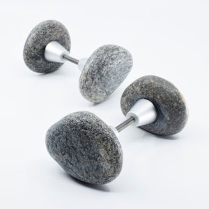 May include: Two grey stone door knobs with silver metal hardware. The knobs are shaped like rounded stones.