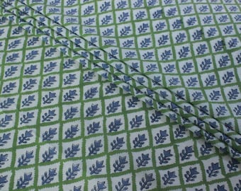 May include: White fabric with a repeating pattern of green squares and blue stylized leaves. The fabric is folded in half.