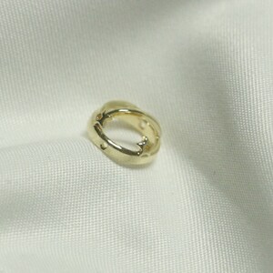 Puede incluir: Un arete de aro dorado con un diseño de corte en forma de estrella.