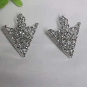以下が含まれることがあります： 繊細なフィリグリーのデザインが施された、銀色の三角形の金属製の装飾が2つです。