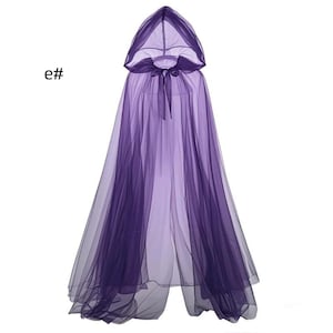 Puede incluir: Una capa morada con capucha que llega hasta el suelo, hecha de tela de tul transparente en capas. La prenda cuenta con una capucha puntiaguda y un cierre de lazo de cinta morada a juego en el cuello. El texto e# es visible arriba a la izquierda.