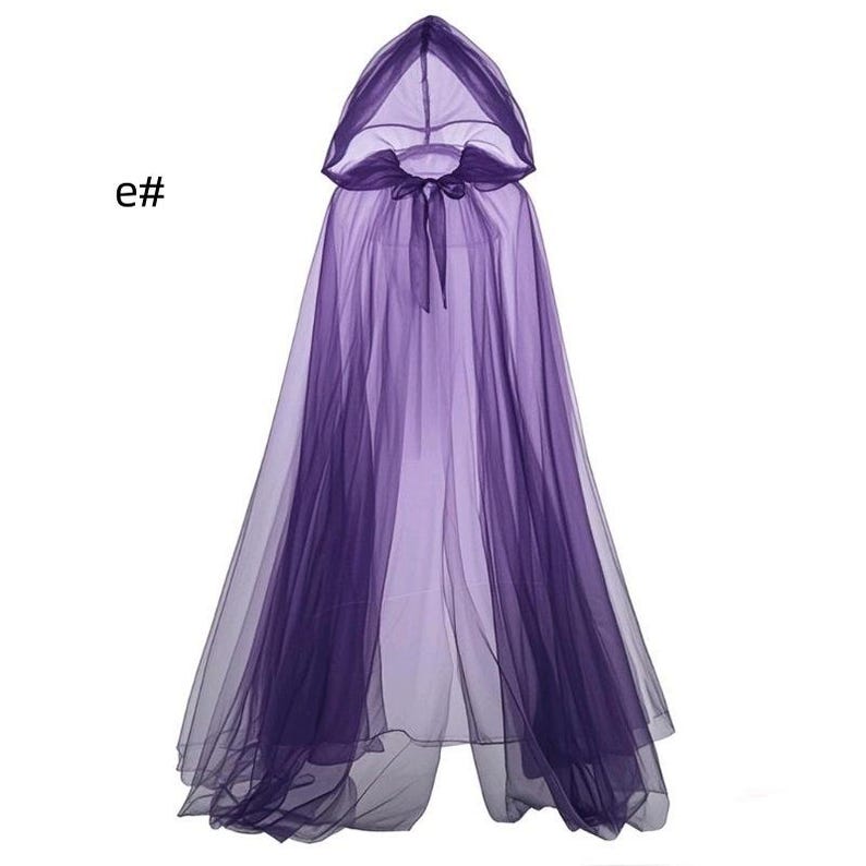 Puede incluir: Una capa morada con capucha que llega hasta el suelo, hecha de tela de tul transparente en capas. La prenda cuenta con una capucha puntiaguda y un cierre de lazo de cinta morada a juego en el cuello. El texto e# es visible arriba a la izquierda.